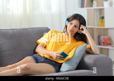 Entspannt jugendlich Musik auf einer Couch im Wohnzimmer zu Hause sitzen Stockfoto