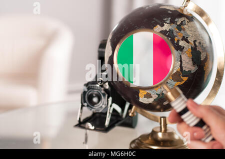 Reisen. Italienische Flagge auf weltkugel unter der Lupe Stockfoto