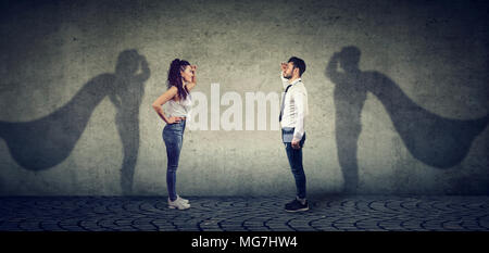 Seitliche Sicht auf einen Mann und eine Frau vorstellen, ein Superheld zu sein, angestrebt. Stockfoto