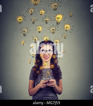 Junge Frau in Brillen holding Smartphone hat viele erfolgreiche Ideen. Stockfoto