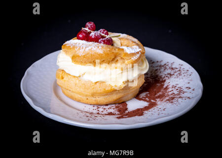 Zeppole mit Creme auf einem Teller, schwarzen Hintergrund für Kopie Stockfoto
