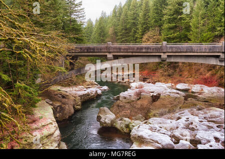 Eine Brücke überquert die East Fork des Lewis River im Clark County, Washington, mit einem leichten Abstauben des Schnees an einem frostigen Wintermorgen in dieser heiteren Stockfoto