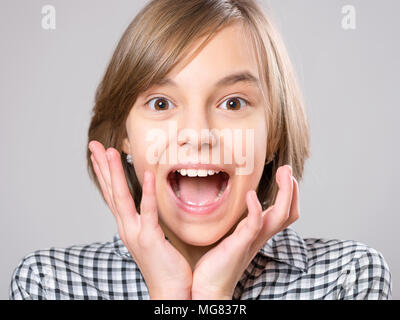 Close-up emotionale Portrait von aufgeregten kleinen Mädchen. Lustig nett überrascht, Kind 10 Jahre alt mit der Mund vor Staunen offen. Schockiert, Teenager, auf grau Bac Stockfoto