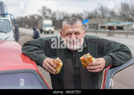 Portrait der Kaukasischen älterer Treiber lyulya Kebab zu essen in der Nähe von seinem Auto lavash Stockfoto
