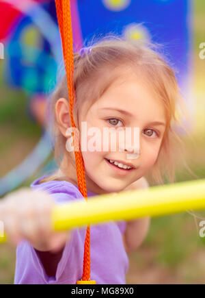 Closeup Portrait einer niedlichen kleinen Mädchen auf der Schaukel am Spielplatz, fröhliches Kind gerne Zeit im Freien verbringen, Baby Mädchen genießen Sport , c Stockfoto