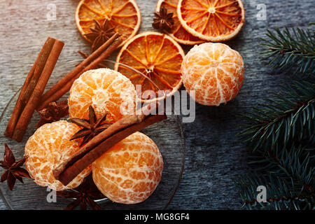 Saftigen Mandarinen Mandarinen ohne Schale liegen auf einer Platte mit Anis und Essstäbchen und Tannenzweigen liegt auf hölzernen Tisch Stockfoto