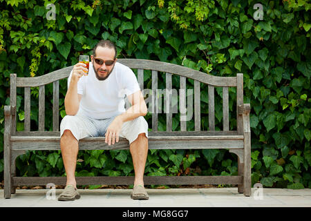 Portrait schießen im Freien der Mann sitzt auf holzbank Stockfoto