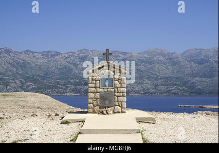 Kleine Kapelle mit Maria Statue auf der Insel Pag Dalmatien, mit dem Velebit Gebirge im Hintergrund in Kroatien Stockfoto