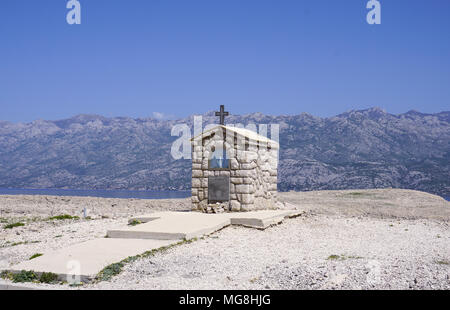 Kleine steinerne Kapelle mit Maria Statue vor der Berg Velebit, am Rande der Insel Pag in Kroatien Stockfoto