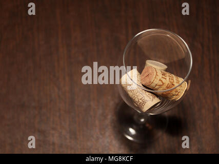 Wein Glas mit drei Korken innen auf einem Holztisch, gesehen Overhead auf der rechten Seite des Rahmens Stockfoto