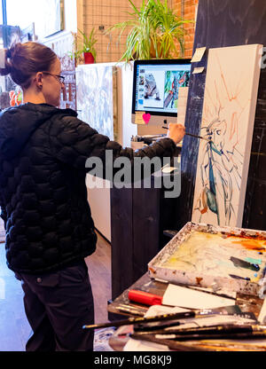 Bildende Künstlerin Katie Maher referenzieren Computer ein Bild beim Erstellen ein Ölgemälde in Ihrer Galerie; Salida, Colorado, USA Stockfoto