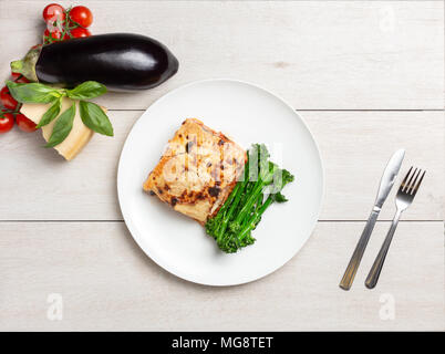 Platz Stück leckere vegetarische Lasagne mit gedünsteten Brokkoli auf eine weiße Platte. Stockfoto