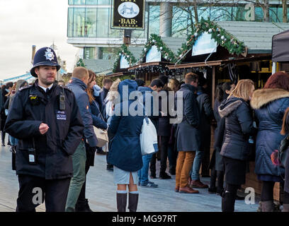 London Polizist Spaziergänge durch an Weihnachten durch den Fluss Open-Air-Markt in London Bridge City, am Südufer der Themse, London. Stockfoto