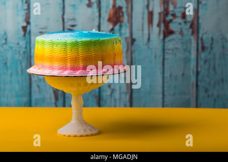 Bunte frosted Kuchen auf Sockel mit gelben und blauen Geschälte Farbe Hintergrund Stockfoto