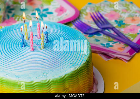 Frosted rainbow Kuchen mit lila Gabeln und Kerzen, Leuchten Stockfoto