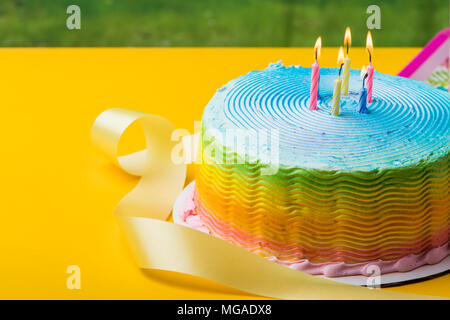 Frosted rainbow Kuchen mit Kerzen und gelbe Band Stockfoto