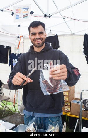 Porträt von einem Anbieter, der eine Probe seiner hausgemachten Beef Jerky bei einem Essen Messe Stockfoto