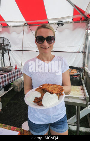 Frau Inhaber eines kleinen Unternehmens, das köstliche Kartoffelpuffer, daß Sie an einem Food Festival gekocht hat Stockfoto