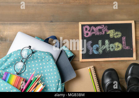 Zurück zu Schule Text auf schwarzen Kreidetafel mit Tasche und Schulmaterial auf Holz Hintergrund, zurück zu Schule und Bildung Konzept Stockfoto