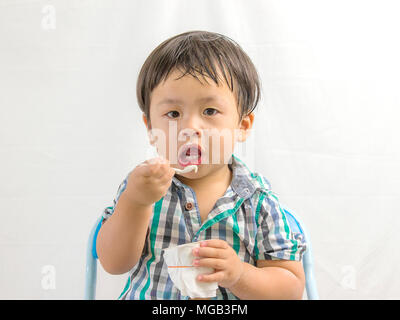 Glücklichen gesunden Jungen essen Joghurt auf Weiß Stockfoto