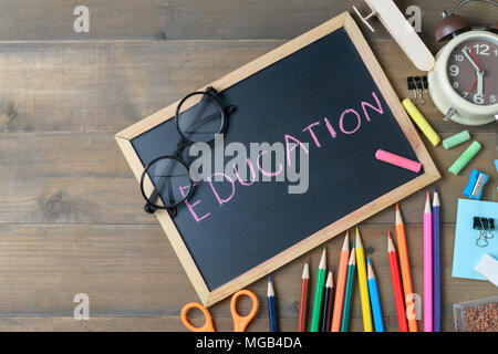 Bildung Text auf schwarzen Kreidetafel mit Brillen und Schulmaterial auf Holz Hintergrund, zurück zu Schule und Bildung Konzept Stockfoto