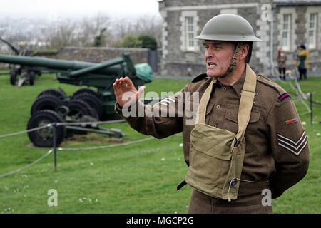 Falmouth, Cornwall, Großbritannien - 12 April 2018: Militärische Historiker in WW2 Royal Artillery sergeant Uniform gekleidet, Erklärung über die Geschütze Abou Stockfoto