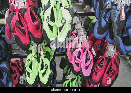 Perranporth, Cornwall, Großbritannien - 9. April 2018: Reef Schuhe oder Aqua schuhe Aufhängen zum Verkauf ausserhalb eines Surf Shop, in Rot, Blau, Grün, Pink. Stockfoto