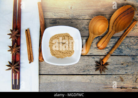 Wärmende Gewürze - Zimt, gemahlener Koriander Samen und Sternanis mit Holzlöffel, Essstäbchen auf vintage Holz Tisch. Stockfoto