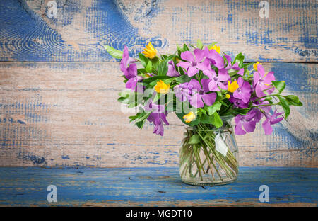 Frühling Blumen im Glas Vase auf dem Hintergrund der alten hölzernen Brettern Stockfoto