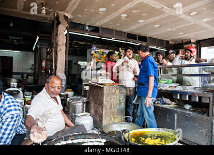 Mumbai, Indien - Dez, 30 2016: ein Mann braten süßen Snacks, während Menschen, die einer Warteschlange Jalebi, die populären indischen süße Wüste kaufen. Stockfoto