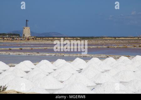 Ein weißer Leuchtturm mit einem roten Dach in der Mitte der Salinen von Marsala, Sizilien, Italien, an einem schönen sonnigen Tag mit blauem Himmel widerspiegelt Stockfoto