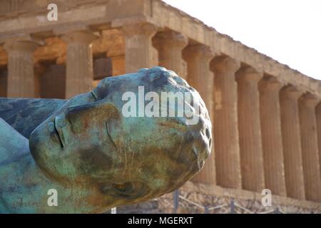 Eine grüne Metal Face, die zu einem Mann, der schläft, während im Hintergrund die Ruinen der Tempel im Tal der Tempel in Agrigento angezeigt Stockfoto