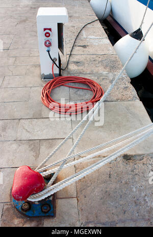 Elektro- und Wasserversorgung Sockel mit Schlauch und Kabel, Bitt- und ein Seil auf der Station befestigt, ein Boot Stockfoto