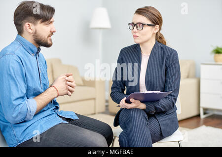 Gut aussehender bärtiger Mann, die unter Depressionen leiden in Absprache mit hoch professionelle Psychiater an gemütlichen Büro, sie ihm mit con Zuhören Stockfoto
