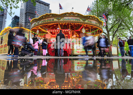 South Bank, London, 28. April 2018. Nach einer eher kalten und nassen Tag über London, Pfützen auf der South Bank, Erstellen bunte Reflexionen eines nahe gelegenen Merry-go-round. Touristen und Einheimische, die das Londoner sind jedoch unbeirrt durch das Wetter, ein Spaziergang entlang des Flusses und das Drängen in die Bars und Cafes in der Nähe der Southbank Centre. Credit: Imageplotter Nachrichten und Sport/Alamy leben Nachrichten Stockfoto