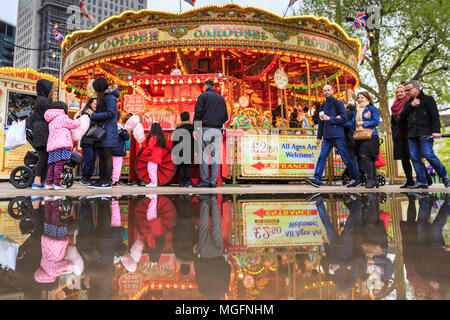 South Bank, London, 28. April 2018. Nach einer eher kalten und nassen Tag über London, Pfützen auf der South Bank, Erstellen bunte Reflexionen eines nahe gelegenen Merry-go-round. Touristen und Einheimische, die das Londoner sind jedoch unbeirrt durch das Wetter, ein Spaziergang entlang des Flusses und das Drängen in die Bars und Cafes in der Nähe der Southbank Centre. Credit: Imageplotter Nachrichten und Sport/Alamy leben Nachrichten Stockfoto