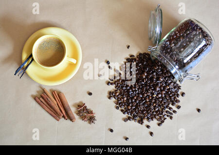 Verschüttete Kaffeebohnen mit einer Tasse Kaffee und Anis, Vanille, Cinnamon Sticks Stockfoto