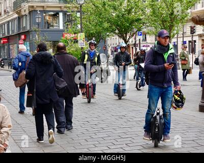 Menschen auf motorisierte Einräder wend ihren Weg durch die Menge der Samstag nachmittag Käufer in der Saint-Paul. Paris, Frankreich. Stockfoto