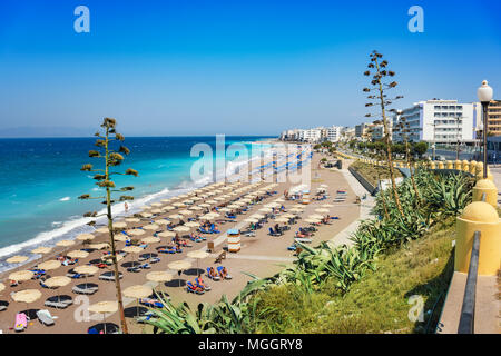 Ägäis Strand mit Sonnenschirmen in der Stadt Rhodes (Rhodos, Griechenland) Stockfoto