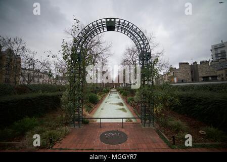 Ein Torbogen und Pfad durch einen Garten mit Blumen und Pflanzen wachsen entlang der Promenade Plantée in Paris Bastille. (Coulée Verte René-Dumont) Stockfoto