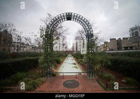 Ein Torbogen und Pfad durch einen Garten mit Blumen und Pflanzen wachsen entlang der Promenade Plantée in Paris Bastille. (Coulée Verte René-Dumont) Stockfoto