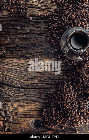 Tasse schwarzen Kaffee mit Bohnen auf Holztisch. Stockfoto