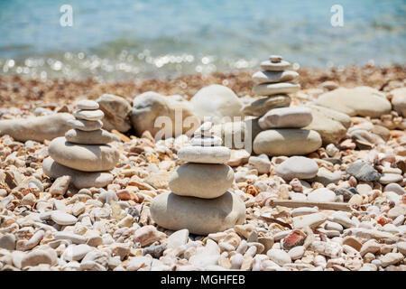 Stapel Steine am meer sommer Strand. Der Haufen der Kieselsteine auf dem steinigen Küste. Steine Pyramide auf Pebble Beach symbolisiert Stabilität, Zen, Harmonie, Balance. Tropische Meer Strand. Ferienhäuser Konzept Stockfoto