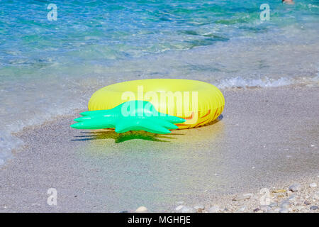 Gelb Schlauchboot paddeln Kreis in Form von Ananas im Sand in der Nähe des Meer. ring schwimmend, in der Nähe des Strandes, bunte aufblasbare Ring zum Schwimmen. Kopieren Sie Platz Stockfoto