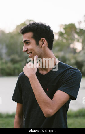 Junge moderne Trendy modische nahen östlichen Indischen männliches Modell Lachen und posiert in der Natur im Park für Portrait Kopf Schüsse Stockfoto