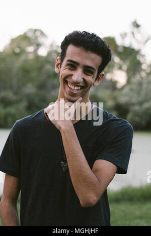 Junge moderne Trendy modische nahen östlichen Indischen männliches Modell Lachen und posiert in der Natur im Park für Portrait Kopf Schüsse Stockfoto