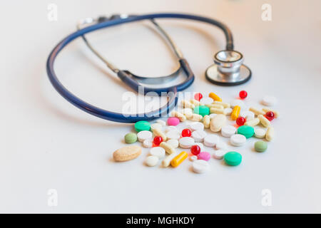 Drogen- und Stethoskope der Arzt medizinische Konzept. Verschiedene verschiedenen Medizin Tabletten und Pillen verschiedene Farben auf weißem Hintergrund. Gesundheit, Herz Konzept Stockfoto