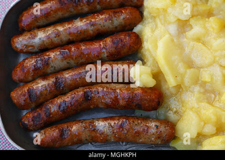 Close up Teil der gegrillten Nürnberger Bratwurst Bratwurst mit Beilage von Kartoffelsalat auf Metall Zinnteller, Erhöhte Ansicht von oben, direkt über Stockfoto