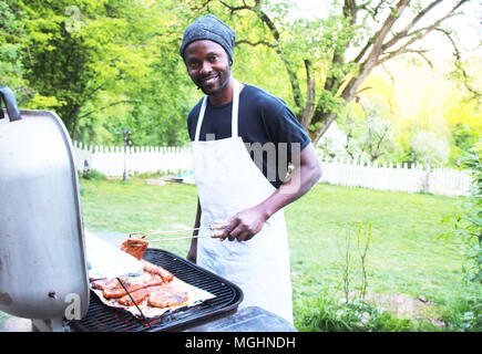 Ein fröhlicher Mann Grills im Freien im Park Stockfoto