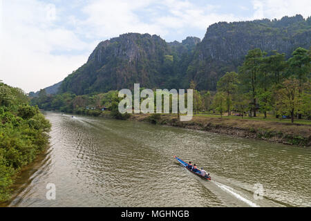 Blick auf drei kleine Boote auf dem Fluss Nam Song und Kalkstein Karst Bergen nahe der Tham Chang (oder Jang oder Jung) Höhle in Vang Vieng, Laos. Stockfoto